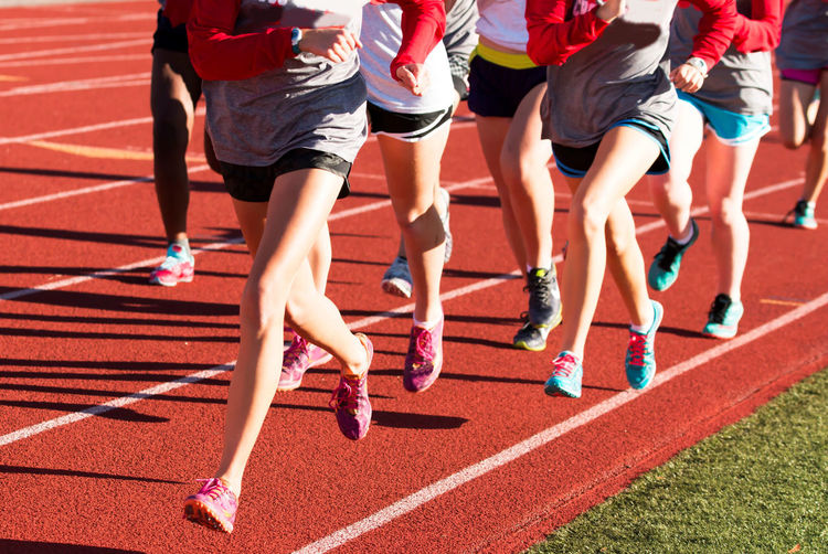 Girls cross country workout running intervals together on a red track while wearing spikes.