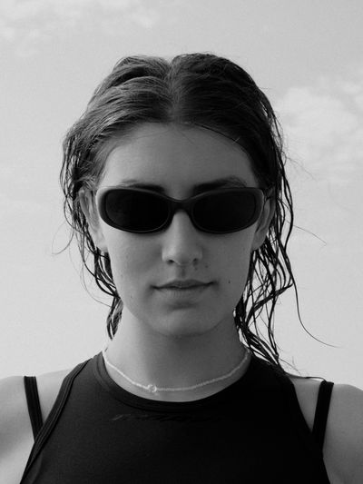 Close-up portrait of woman with sunglasses against sky