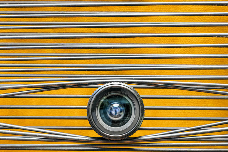 Close-up of camera lens against yellow background
