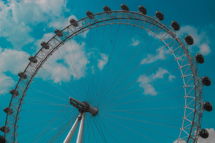 Low angle view of ferris wheel against cloudy sky