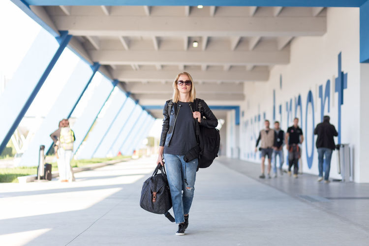 Full length portrait of young woman walking on airport