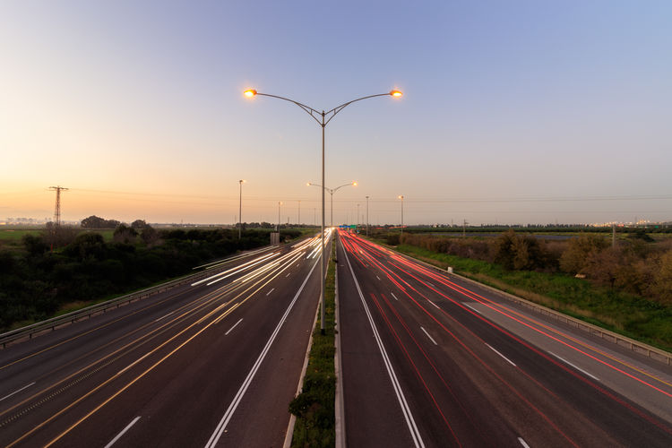 Light trails on highway against sky