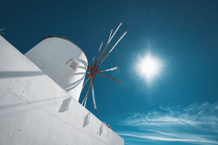 Low angle view of windmill against blue sky on sunny day