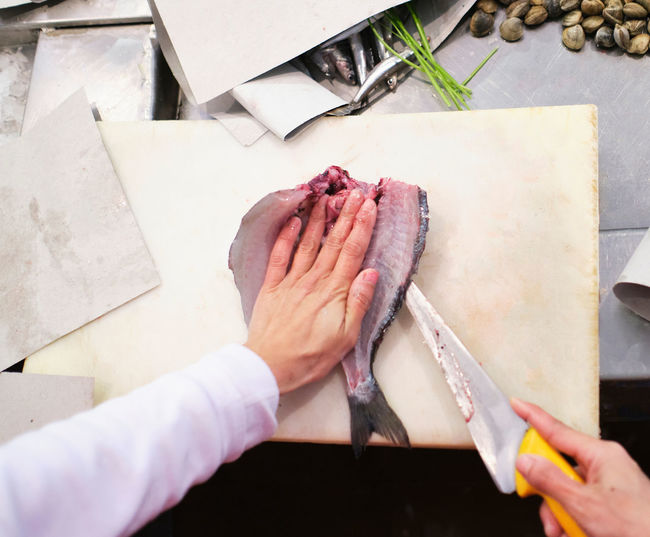 Young woman cuts up a red fish in her fishmonger's