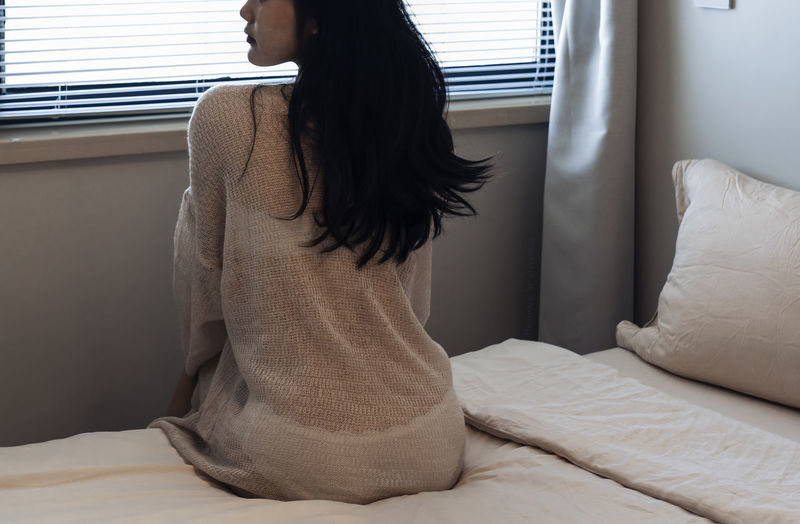 Young woman sitting on bed at home