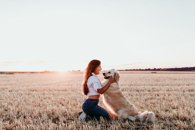 Woman with dog on field against clear sky