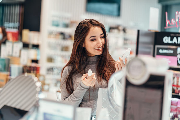 Smiling young woman shopping at cosmetic store