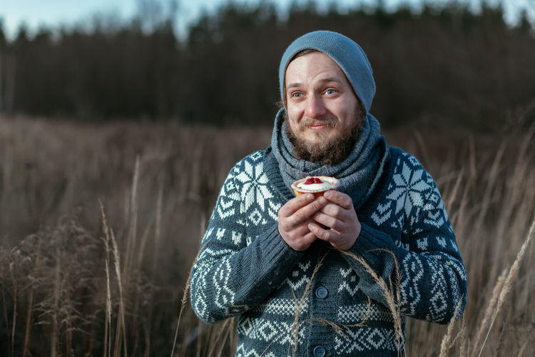 Smiling man holding dessert while standing on field