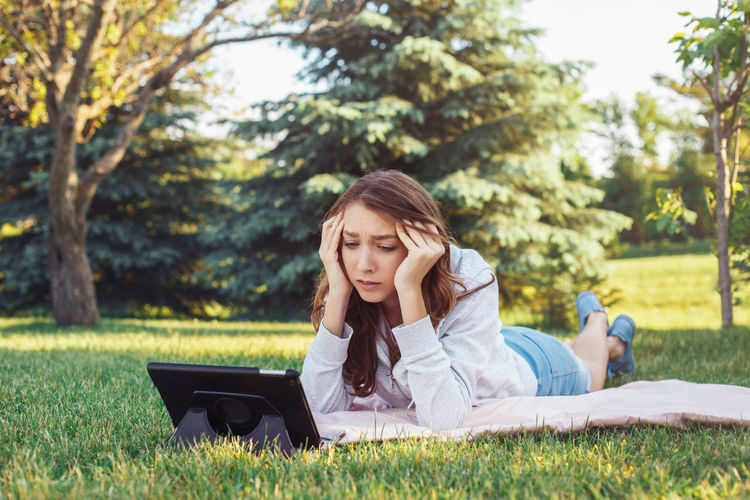 Young woman looking away while sitting on grass