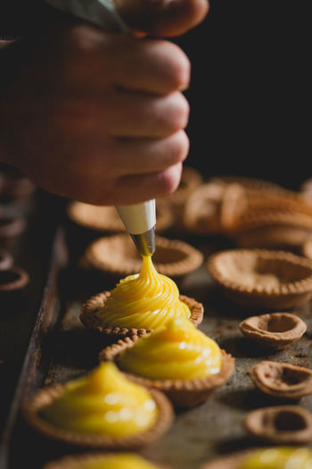 Close-up of baker piping mixture into pastries