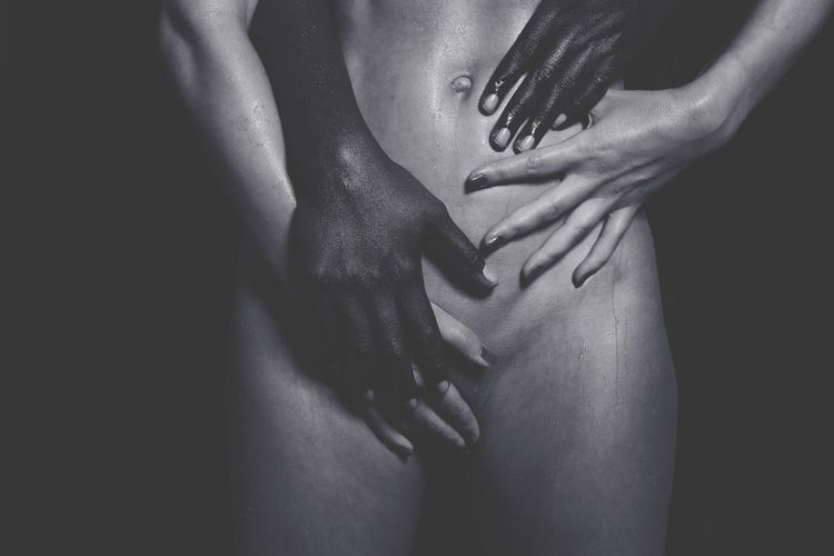 Midsection of naked sensuous couple romancing against black background