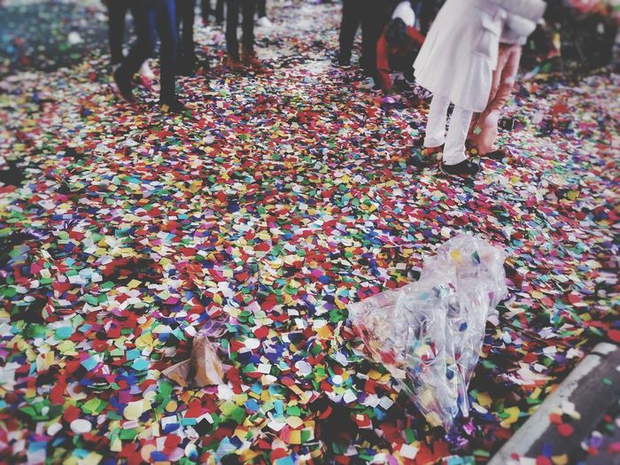 Low section of people walking on confetti covered street