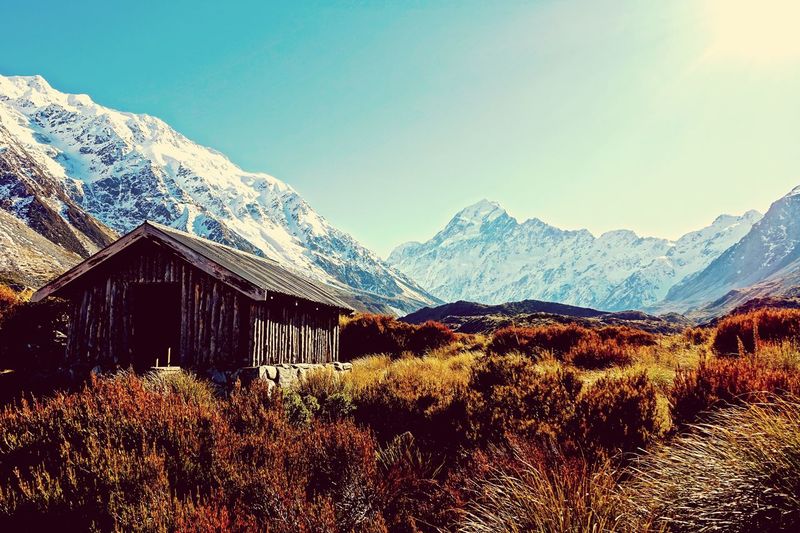 House on field against snowcapped mountain