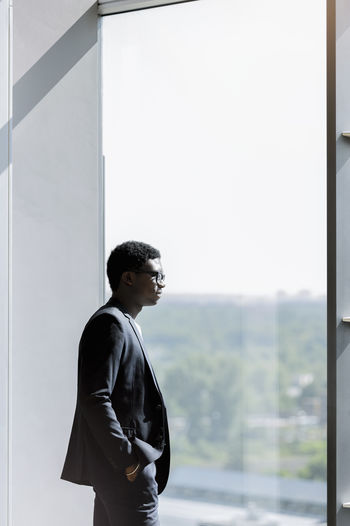 Thoughtful male entrepreneur with hand in pocket looking away at office