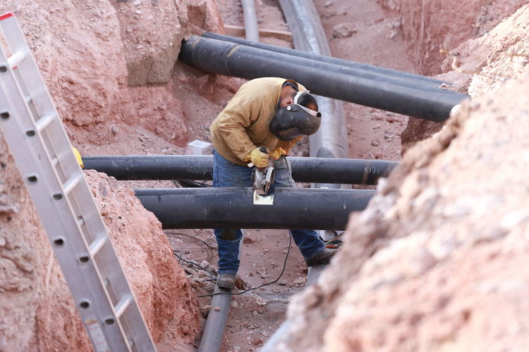 High angle view of worker welding metallic pipe