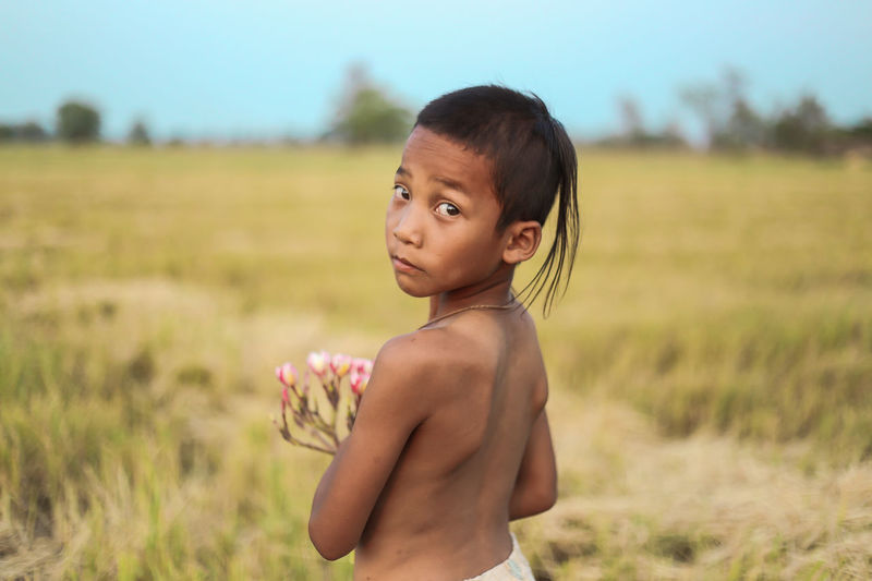 Portrait of shirtless boy standing on field