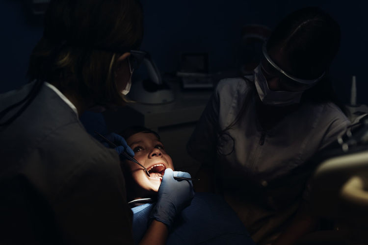 Dentists examining boy in clinic