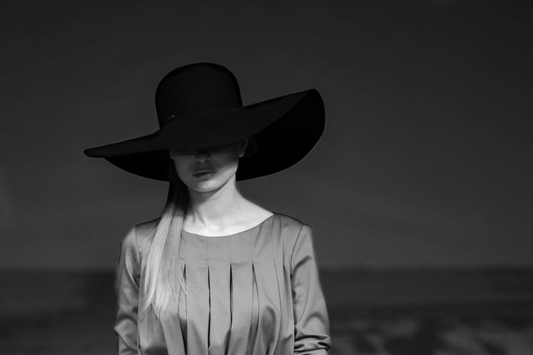 Woman wearing hat standing against sea