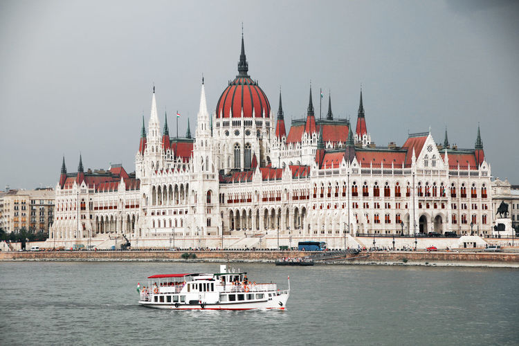 Boat in river by hungarian parliament building in city