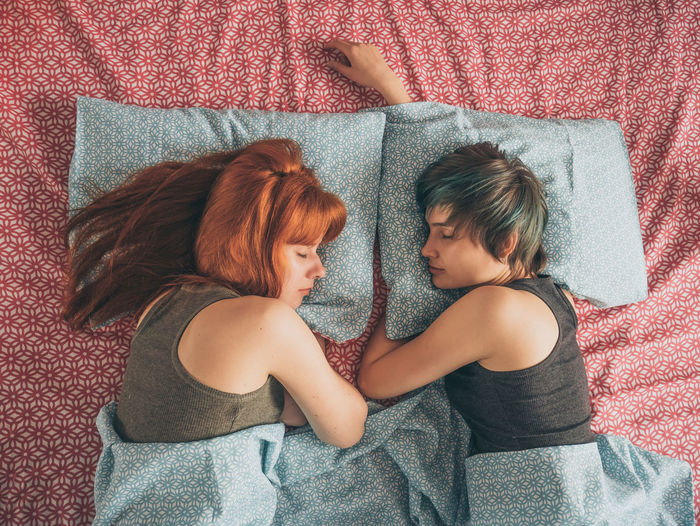 Lesbian couple sleeping on bed at home