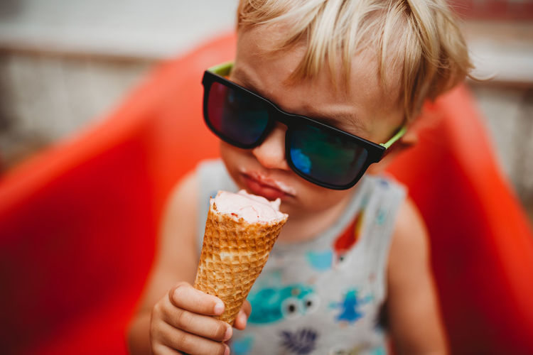 White blonde toddler eating ice cream cone with sunglasses