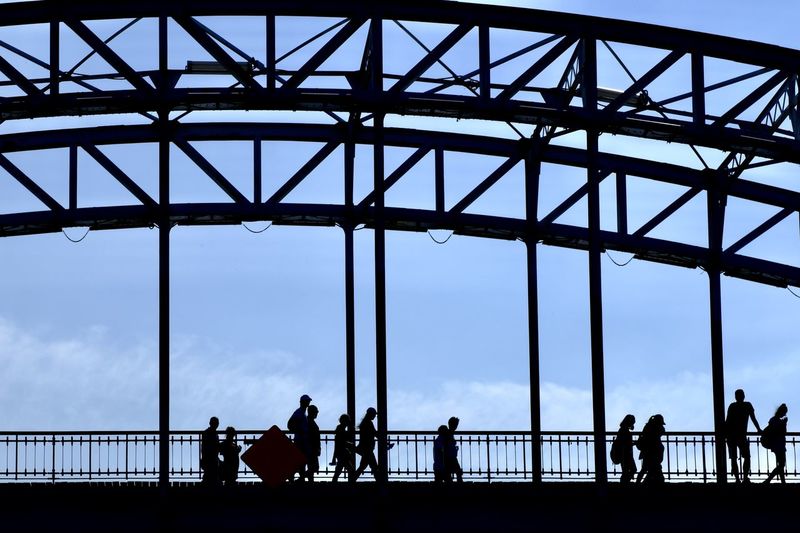 Silhouette people on bridge against sky
