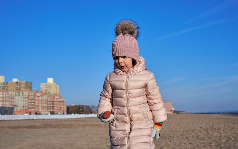 Young girl playing on the beach in winter dressed in a warm coat