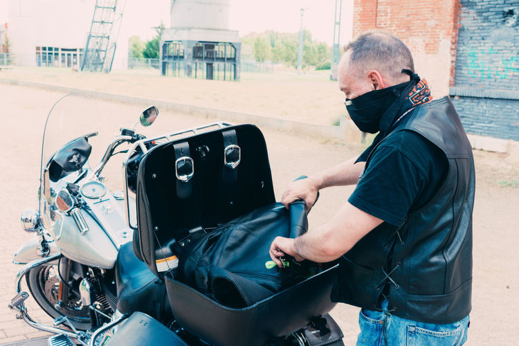 Motorcyclist putting jacket in motorcycle suitcase