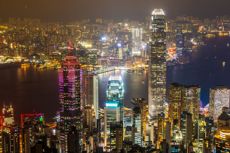 Illuminated buildings at victoria harbour in city during night