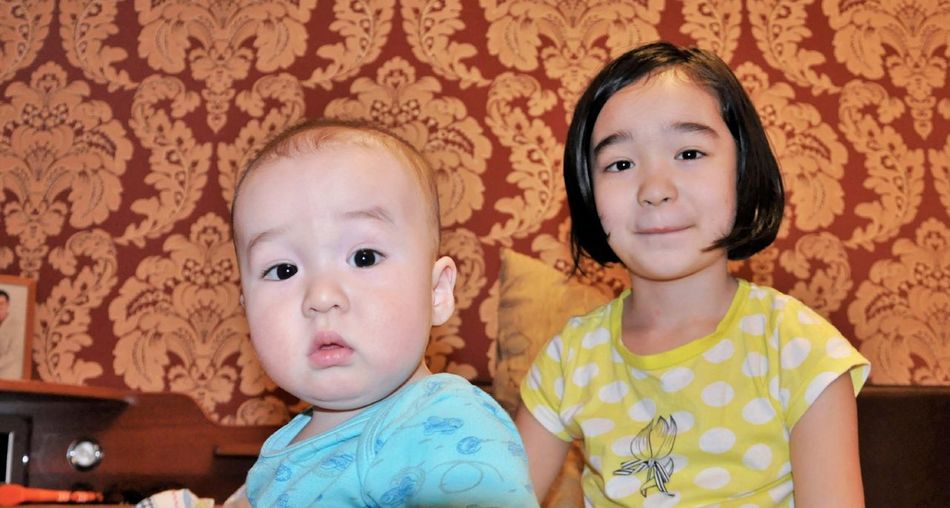 Portrait of cute siblings sitting at home