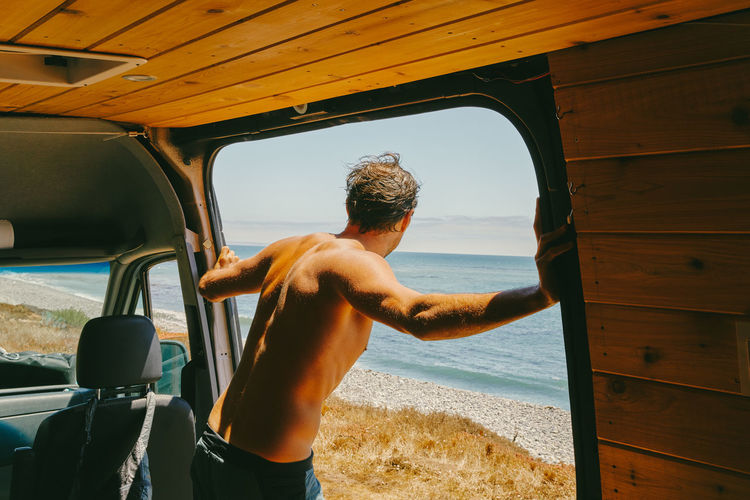 Man looking out to ocean through van door in baja california, mexico
