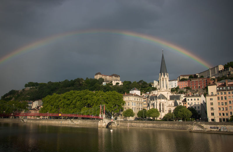 Scenic view of rainbow over river and buildings in lyon city