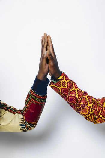 Closeup shot of anonymous couple in trendy african outfit standing on white background in studio