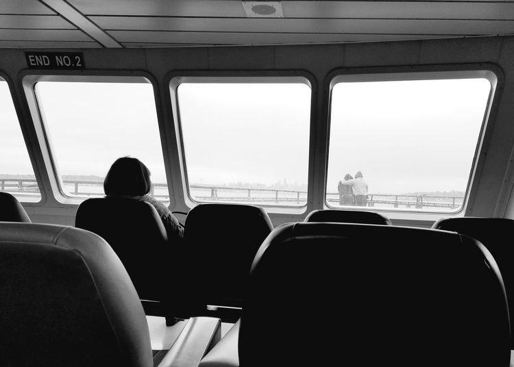 Woman looking through ferry window at couple hugging