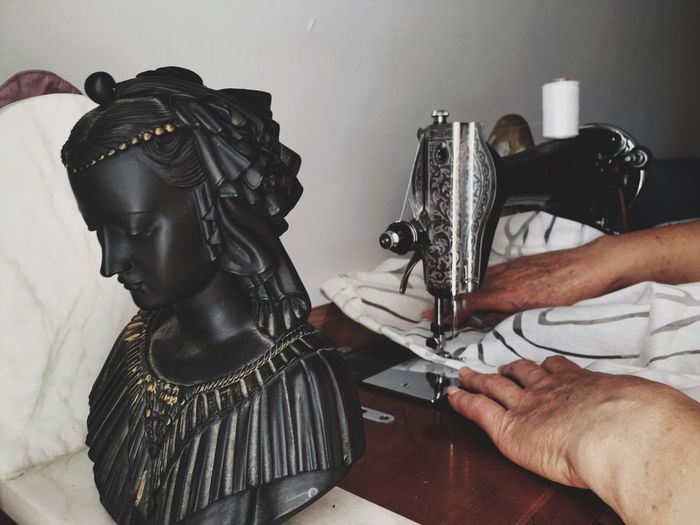 High angle view of statue by cropped woman using sewing machine