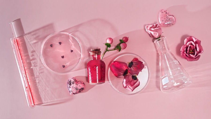 Love potion glass bottle with chemical glassware, flowers and petals.  chemistry of love