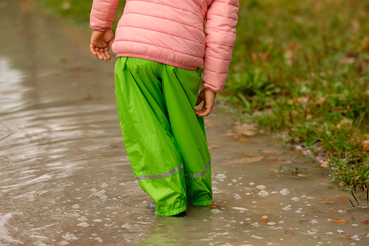 Low section of woman standing on wet road