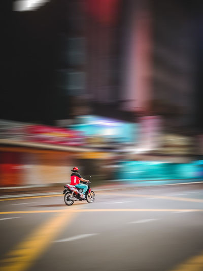 Blurred motion of man riding motorcycle on road
