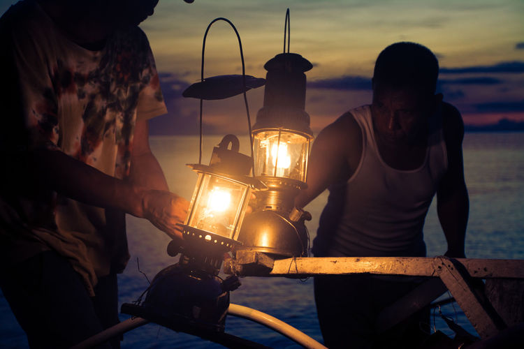 Men with illuminated lanterns at beach