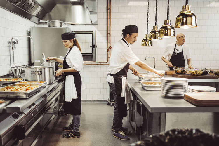 Kvinnlig och manlig kock arbetar i restaurangkök