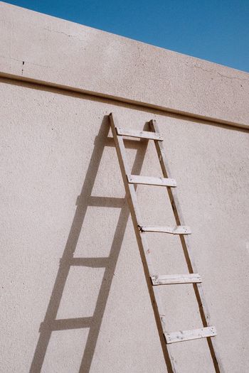 LOW ANGLE VIEW OF LADDER ON BUILDING WALL