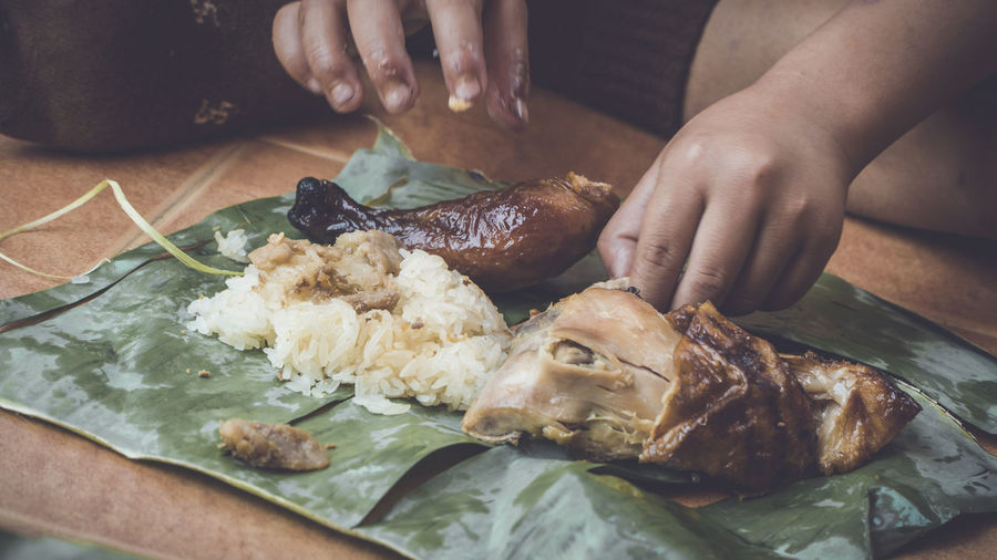 Close-up of hand eating food in banana leaf 