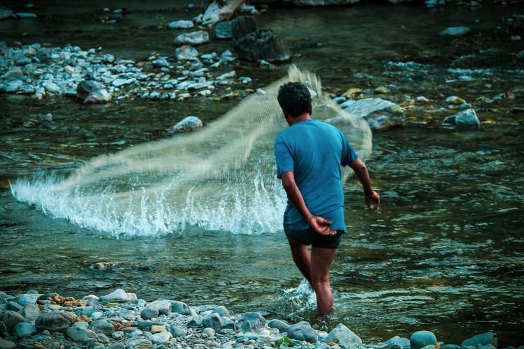 Rear view of man walking in river
