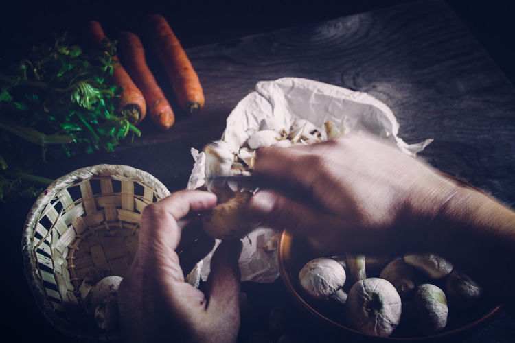 Cropped image of chef peeling mushroom on table