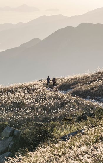 People sitting on mountain against sky