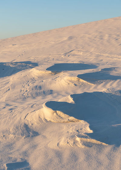 Hard sand formations poking through the white sands dunes at sunset in white sands national park