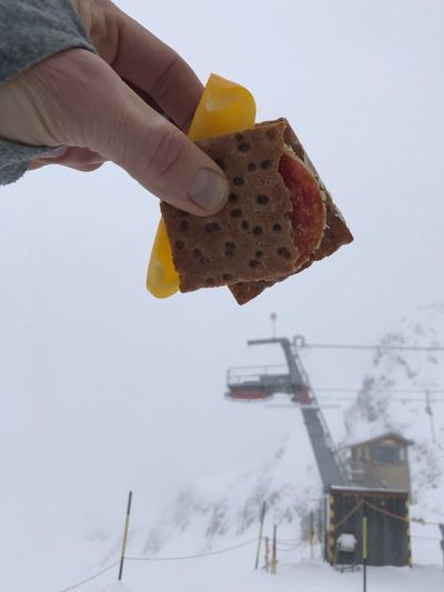 Midsection of person holding ice cream against clear sky during winter