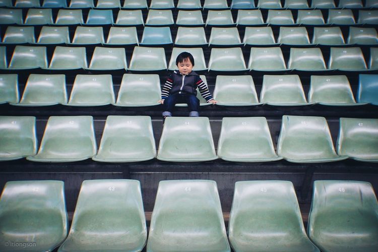 Boy sitting on chair in stadium
