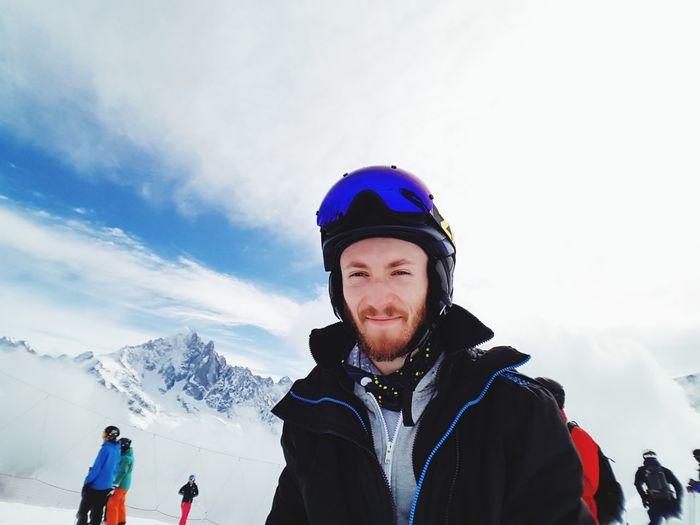 Portrait of smiling man on snow mountain against sky