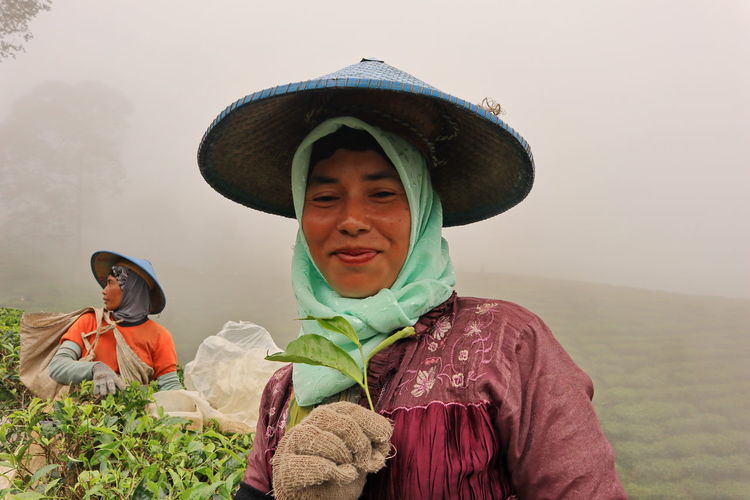 Smiling woman working in farm against sky